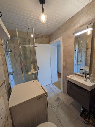 kleines Badezimmer mit Dusche und Waschmaschine