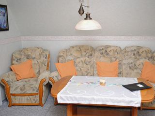 Wohnzimmer mit Küchenzeile FlachbildTV und Couchgarnitur zum gemütlichen Sitzen