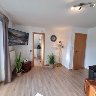 Wohnzimmer mit Fernseher und Blick in die Küche