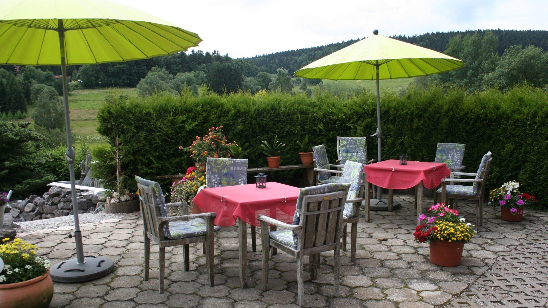 Blick auf die Terrasse mit Gartenmöbeln und Sonnenschirmen