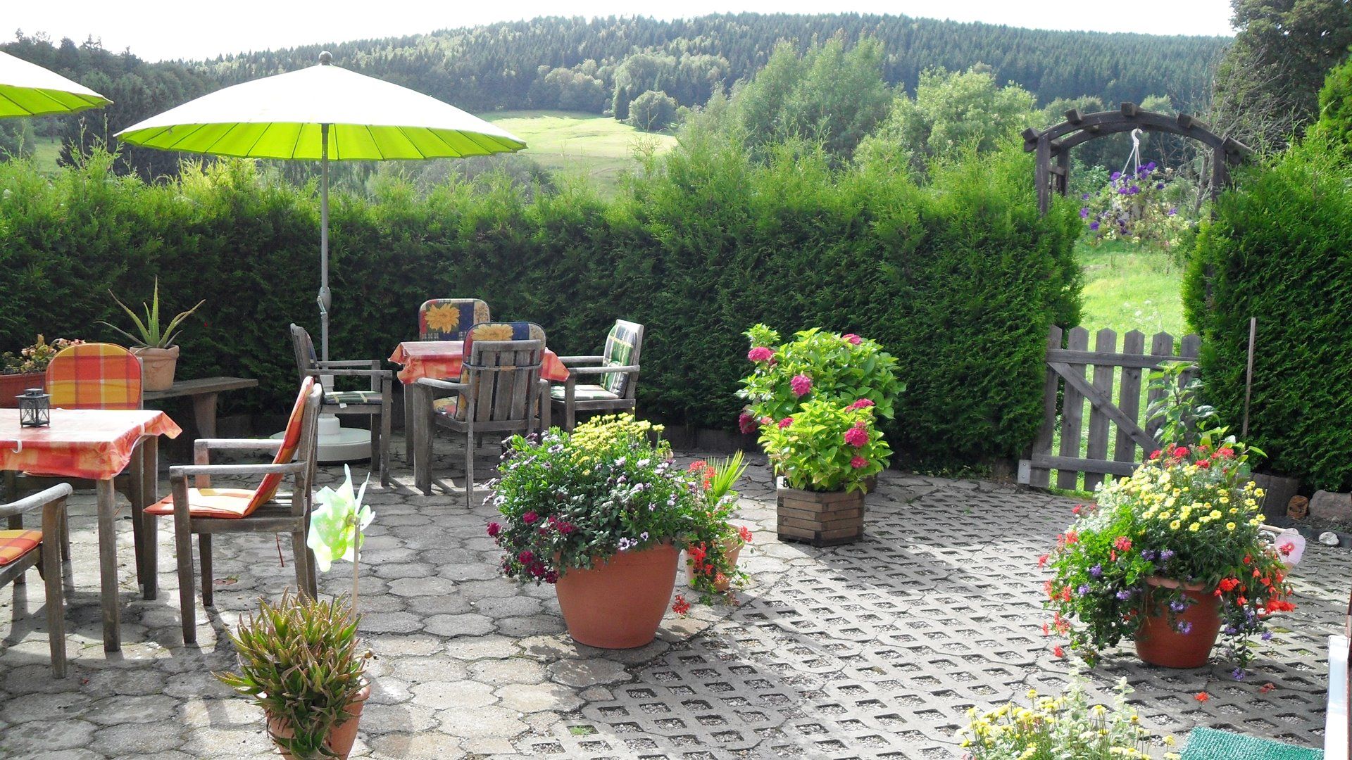 Blick auf die Terrasse mit Gartenmöbeln und Sonnenschirmen