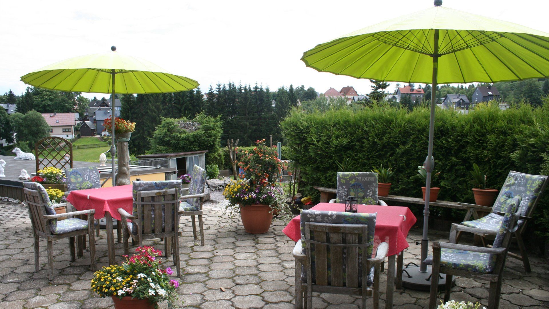 Blick auf die Terrasse mit Gartenmöbeln und Sonnenschirmen